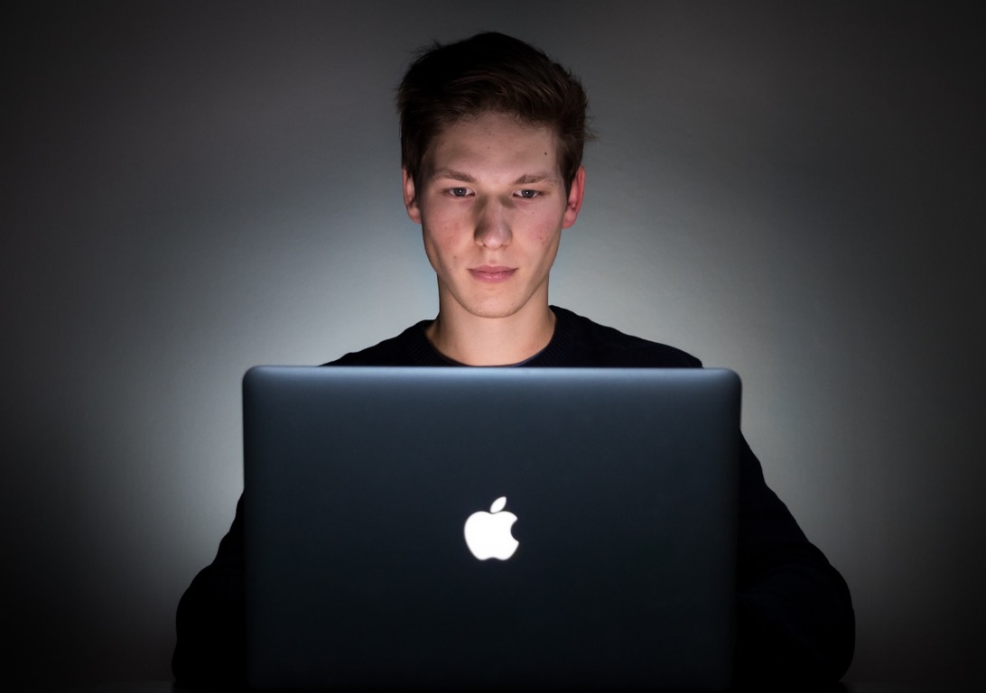 Boy using a laptop illuminated by the screen